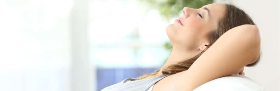 Woman relaxing on a couch, enjoying clean air and comfort, reflecting the importance of HVAC services for indoor air quality.