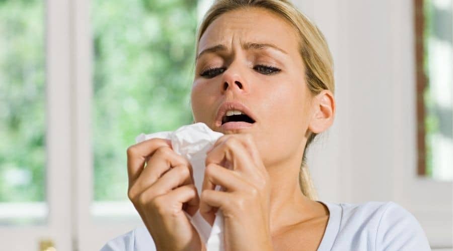 Concerned woman holding tissue in indoor setting, illustrating need for comfort and HVAC solutions.