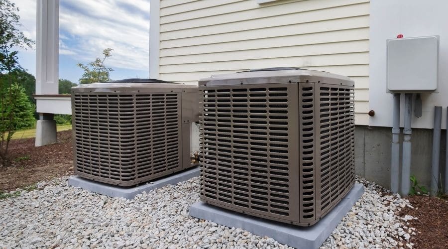 Two air conditioning units on a gravel base, showcasing Barker Heating & Cooling's HVAC solutions in a clean outdoor setting.