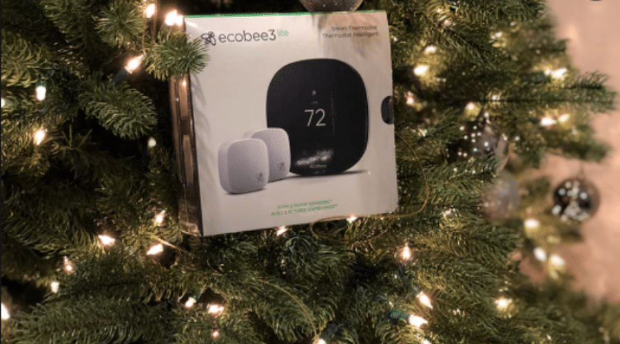 Ecobee Smart Thermostat with sensor and packaging near Christmas tree for HVAC comfort solutions.