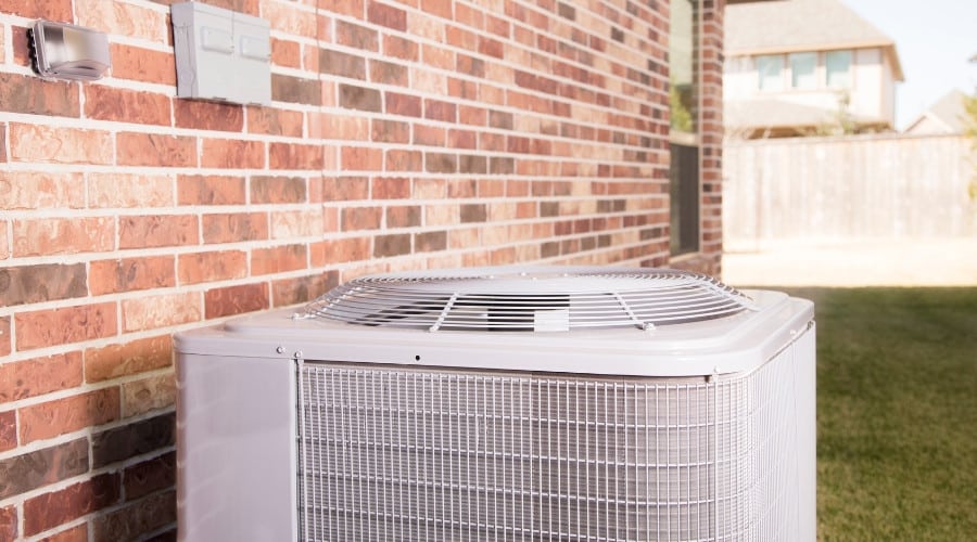 Air conditioning unit installed outside a brick wall, emphasizing home comfort services related to heating and cooling.
